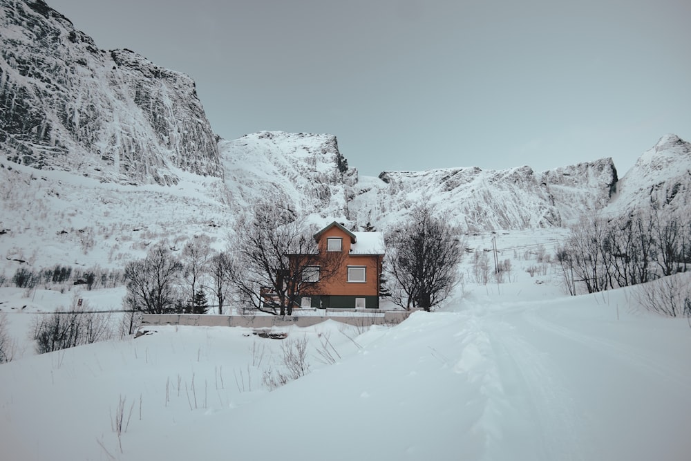 brown house on snow covered ground near snow covered mountain during daytime