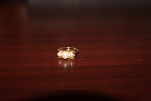A classic gold ring with a smooth finish displayed on a polished wooden surface.