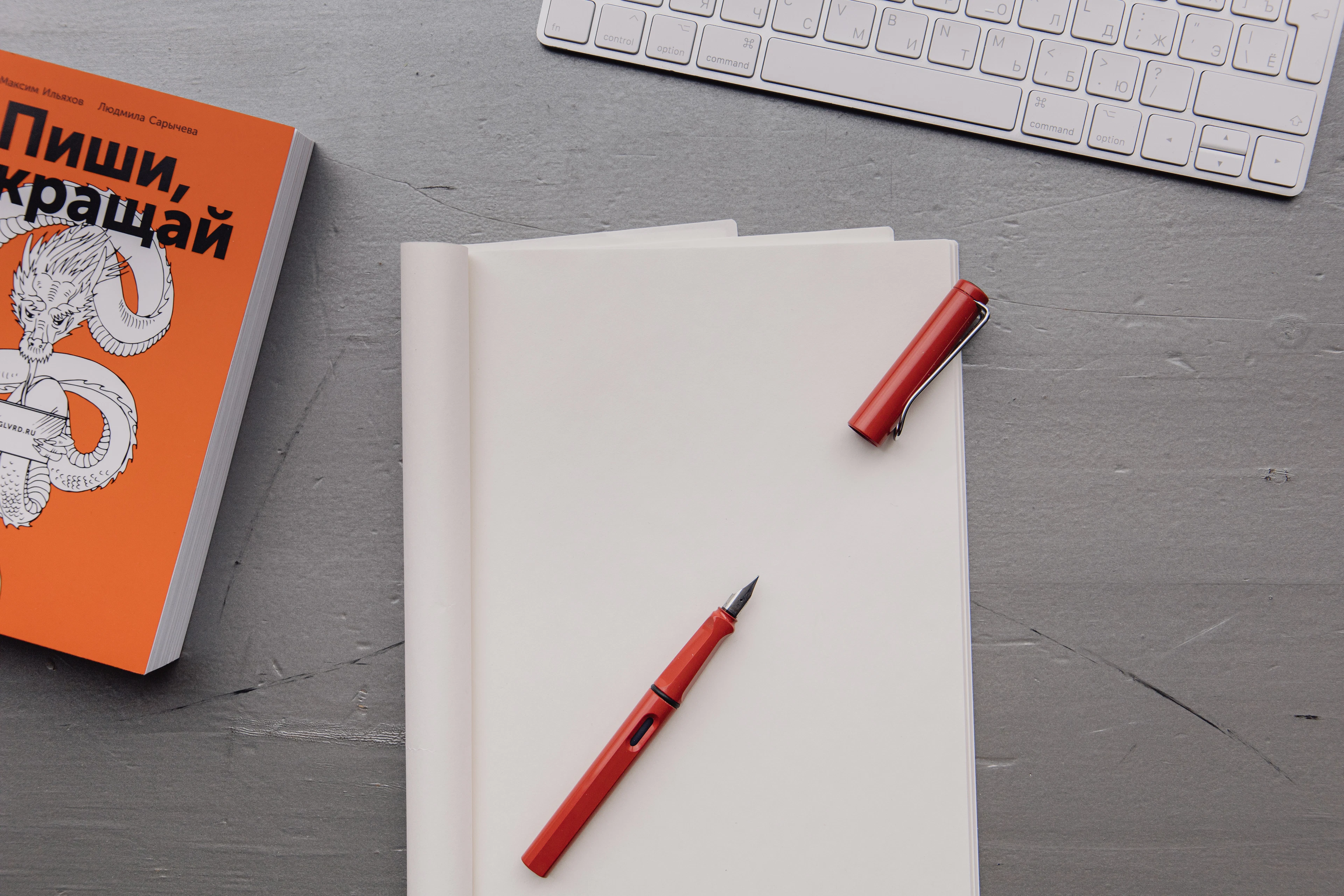 A red pen beside a notebook and keyboard on an editor's desk