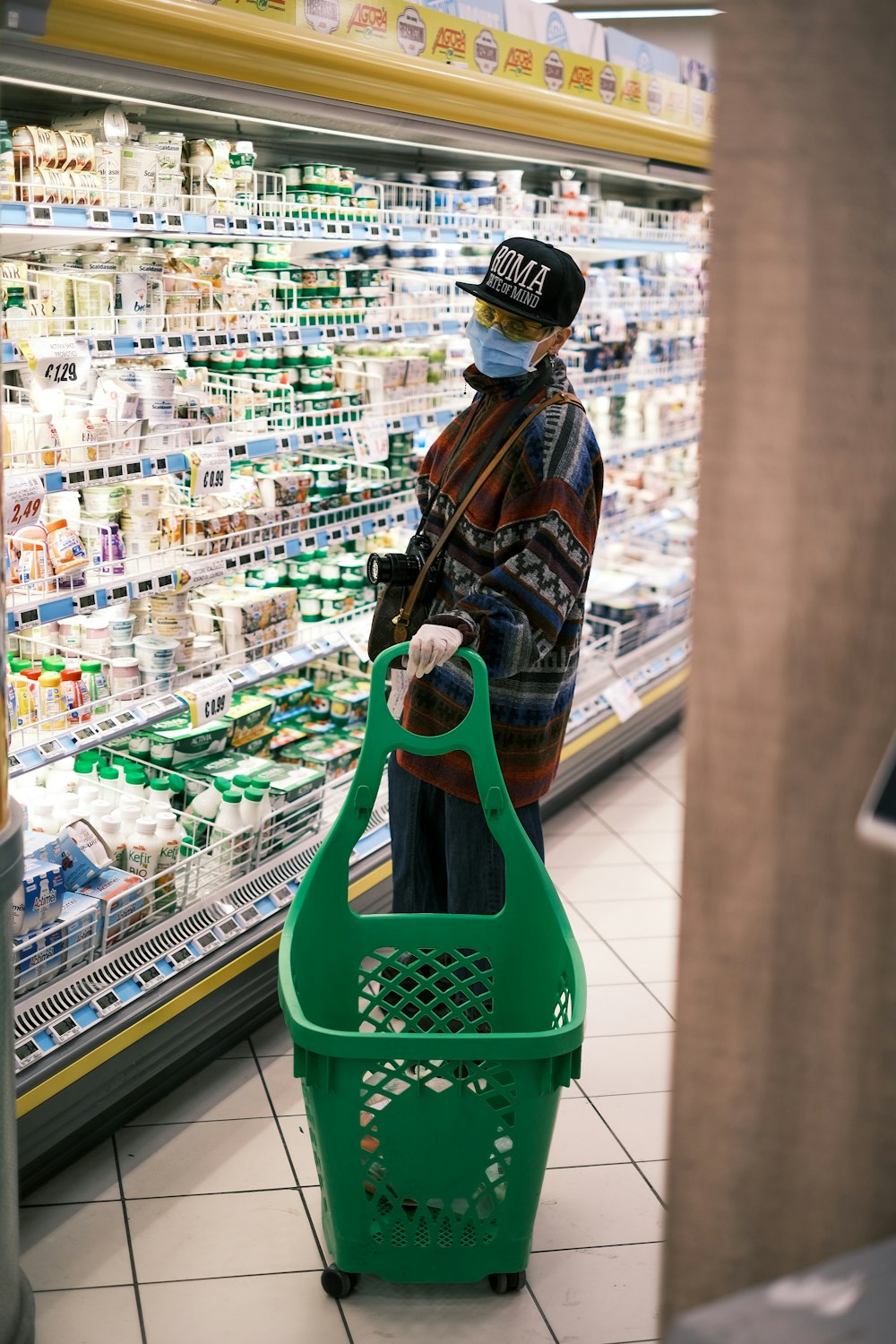 woman in brown and black jacket holding green plastic shopping basket