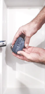 Close-up of a sleek acrylic soap dish holding a bar of soap beside a modern sink.