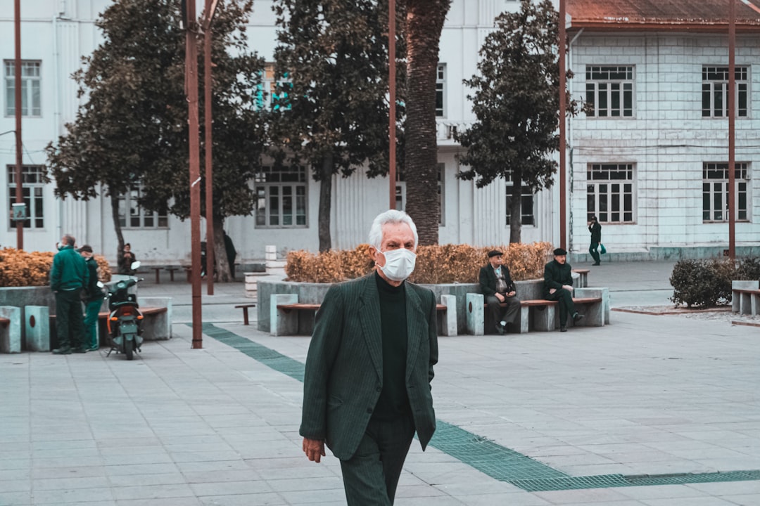 man in green coat standing on gray concrete floor