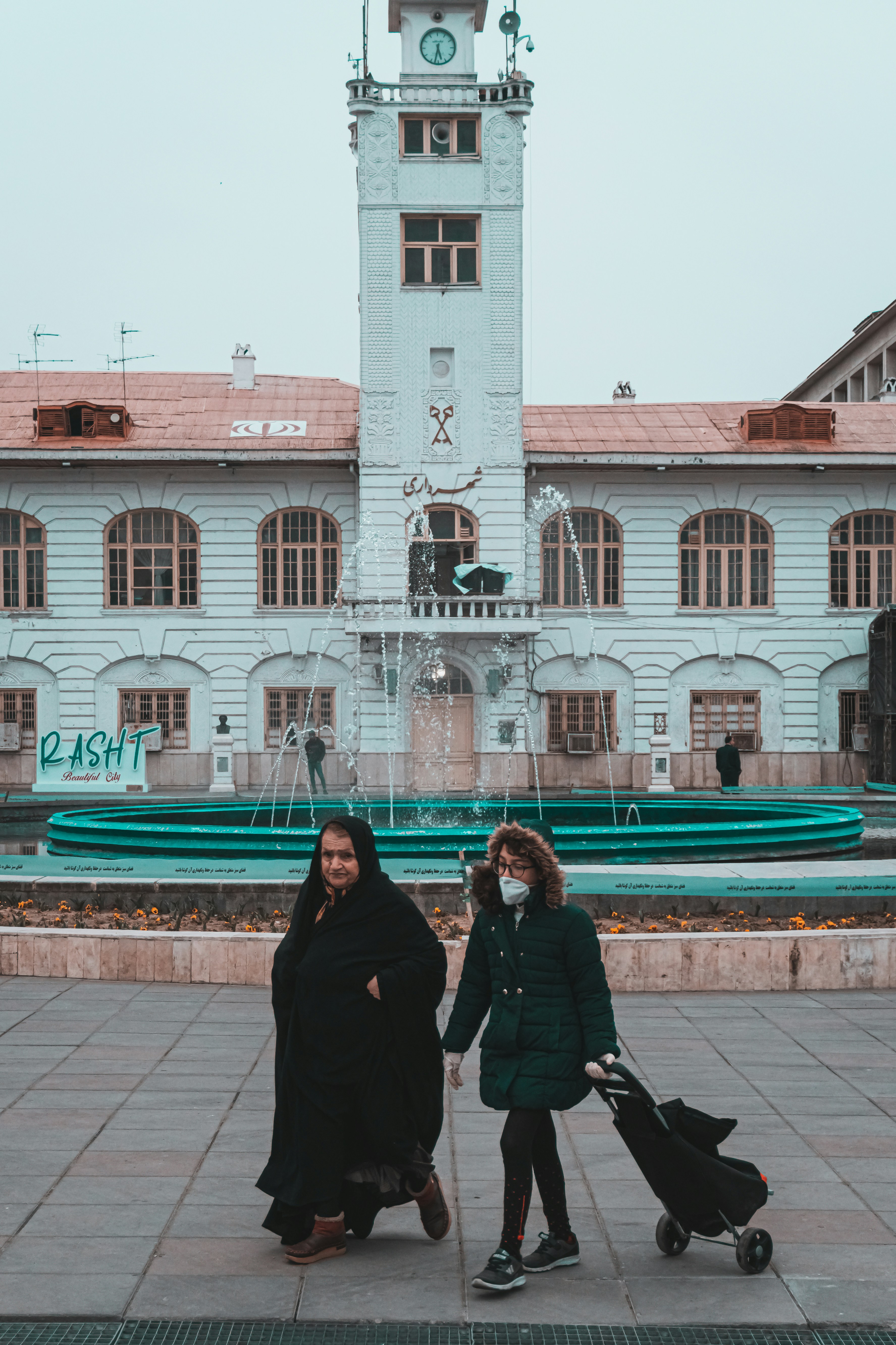 2 women standing near white concrete building during daytime