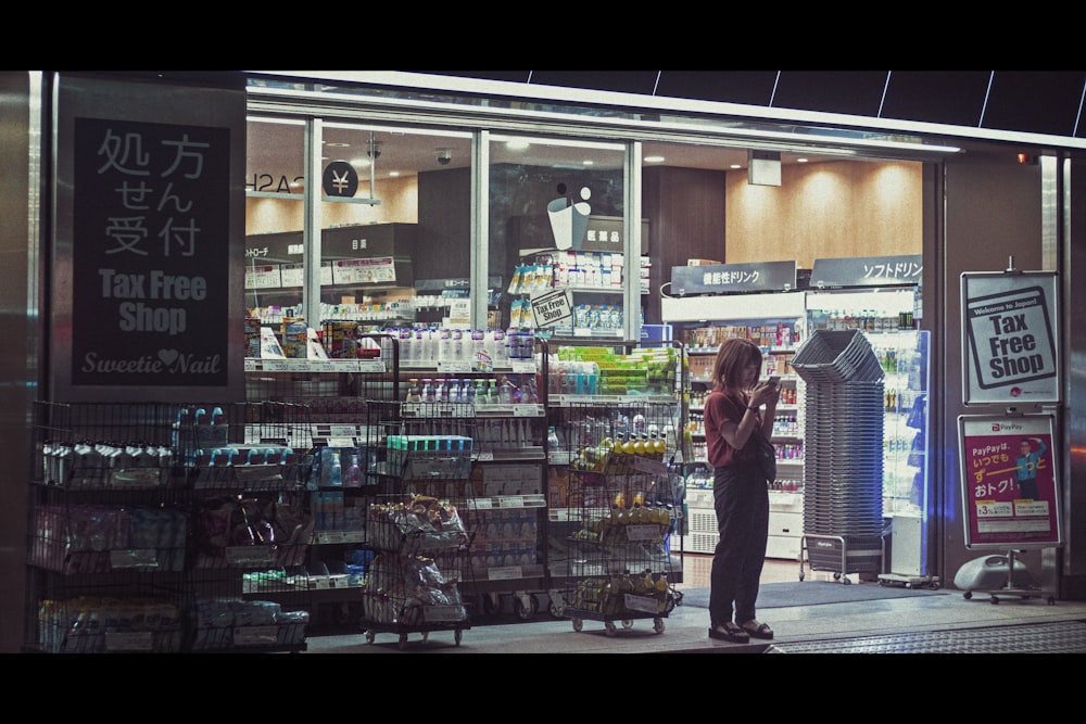 man in red and black plaid dress shirt and black pants standing in front of store