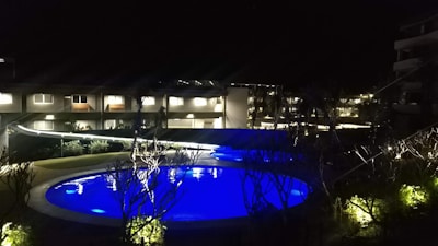 A sparkling pool with automated lighting glowing softly in the evening, framed by lush greenery.