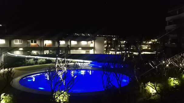 Nighttime shot of a pool with cobalt blue illumination contrasting against dark anthracite decking.