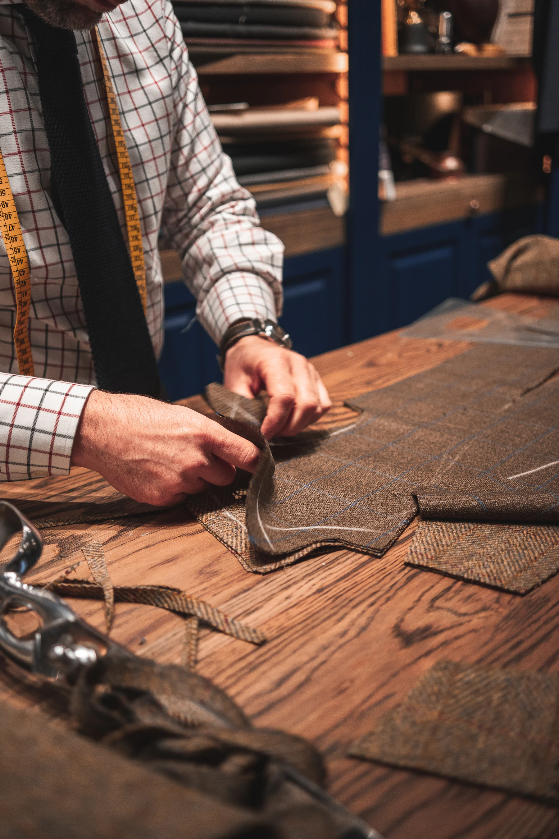 A tailor cutting cloth on a workbench.