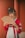 A person in traditional clothing holds a decorative hand fan. The outfit features intricate embroidery, and the hair is styled with ornamental accessories.