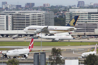 An airplane taking off from Singapore airport with cargo containers visible.