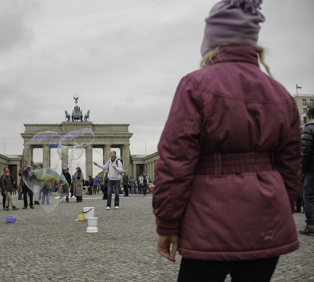 woman in pink coat walking on gray concrete pathway during daytime