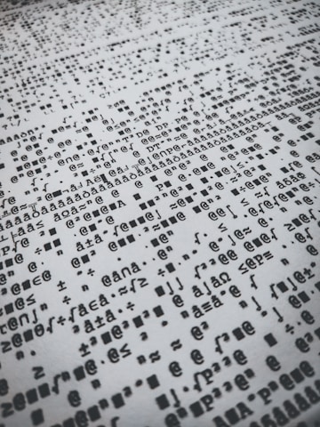 Rows of distorted, random, and overlapping characters and symbols in black on a white background create a chaotic pattern.