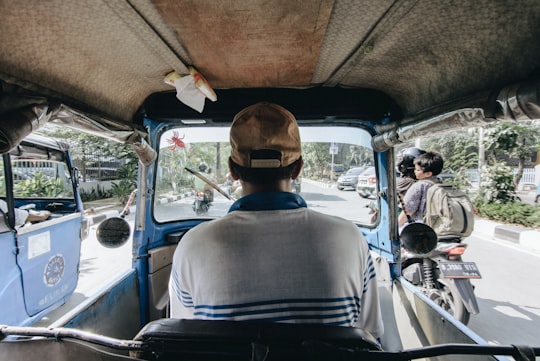 man in blue shirt wearing brown hat sitting on car seat in Jakarta Indonesia