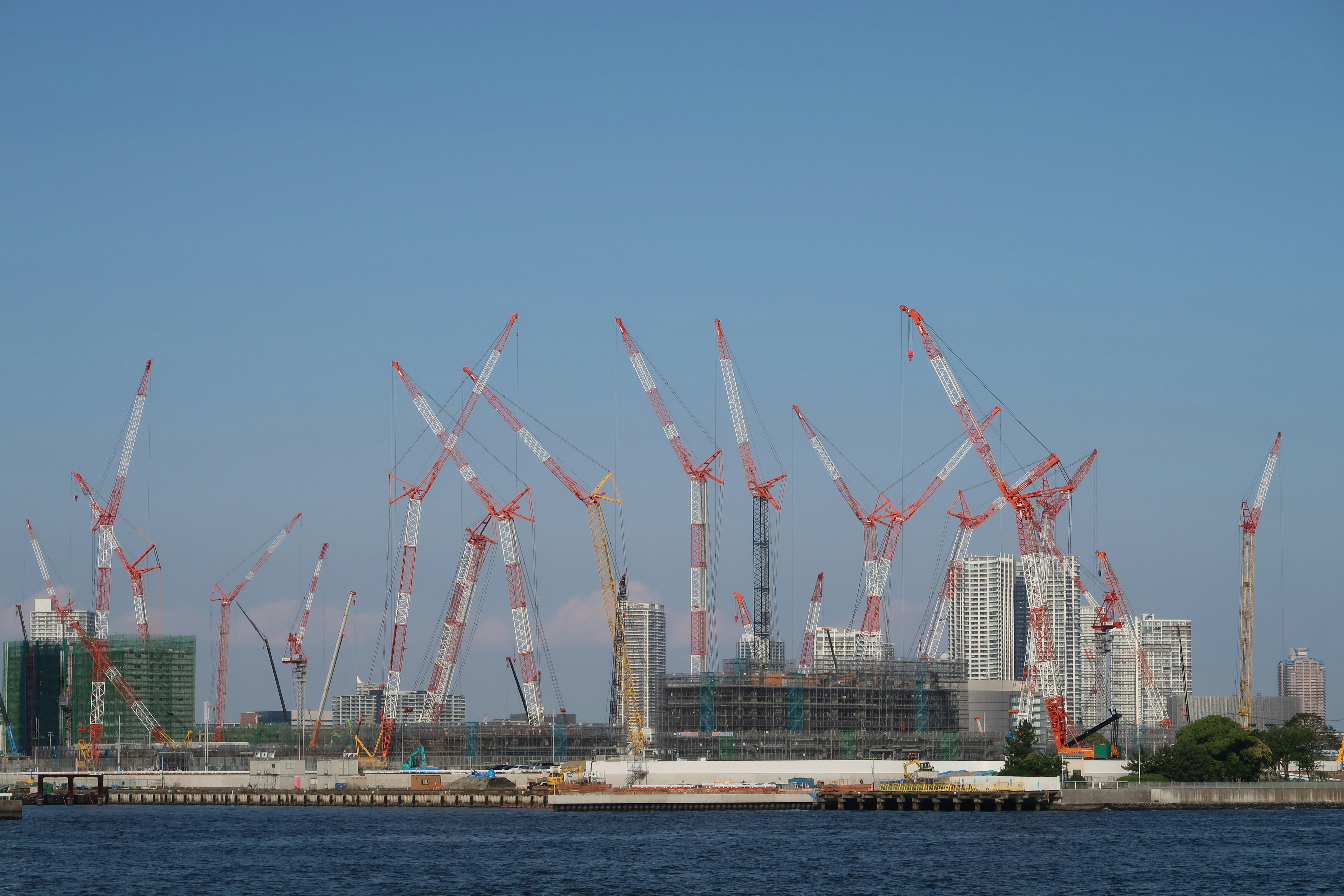 日中の水域近くの白と赤の金属製の塔