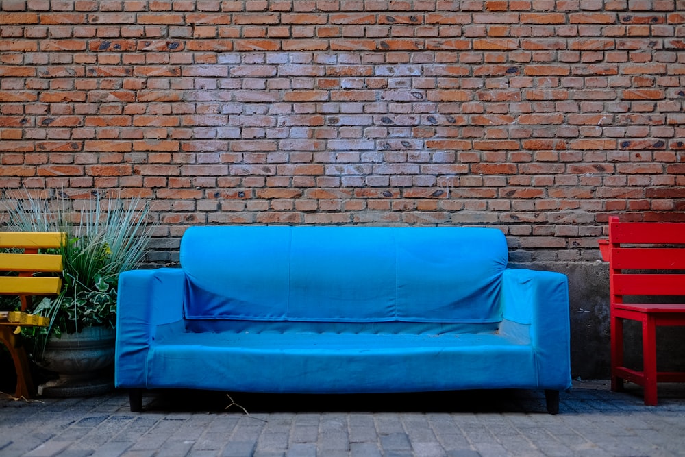 blue couch beside brown brick wall