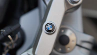BMW branded merchandise including caps, keychains, and jackets showcased on a white surface.
