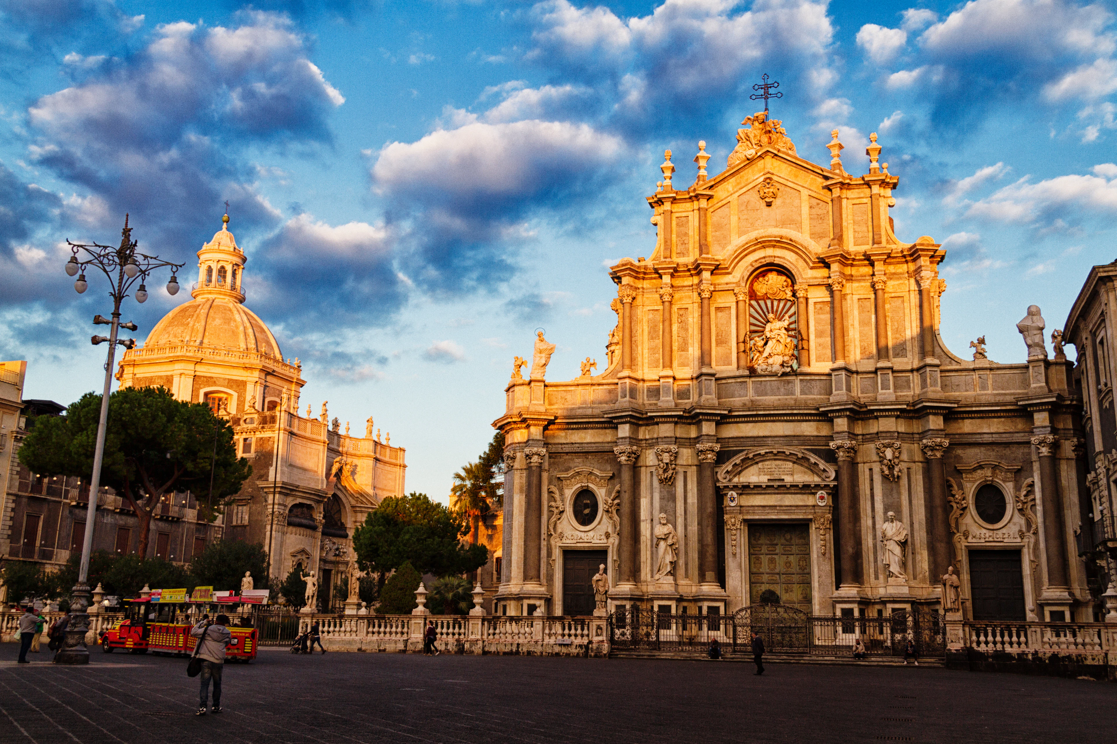 The baroque facade of Catania Cathedral glowing at golden hour on Piazza del Duomo