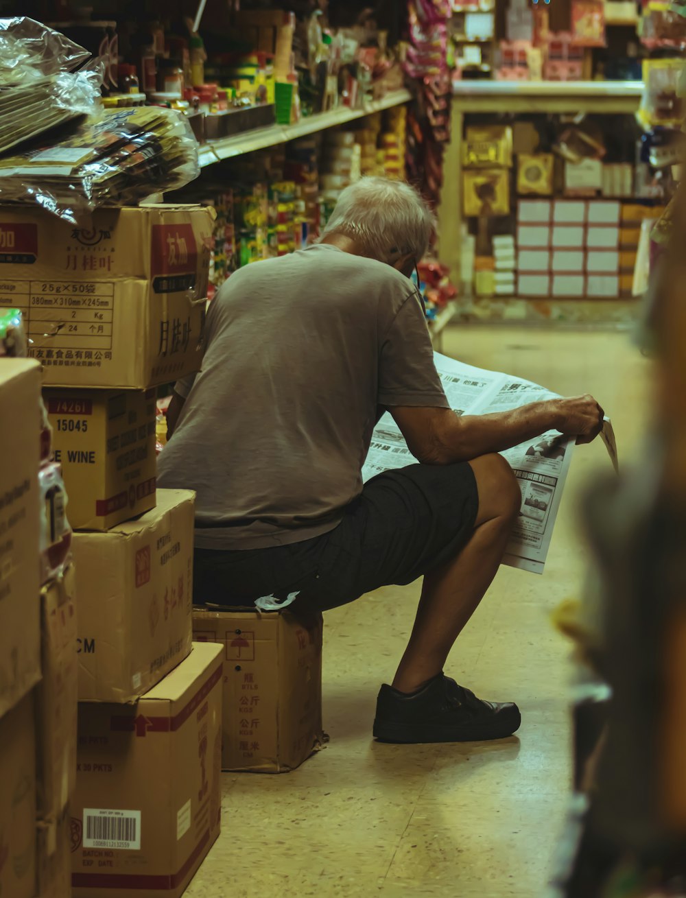 man in gray t-shirt and black pants holding newspaper