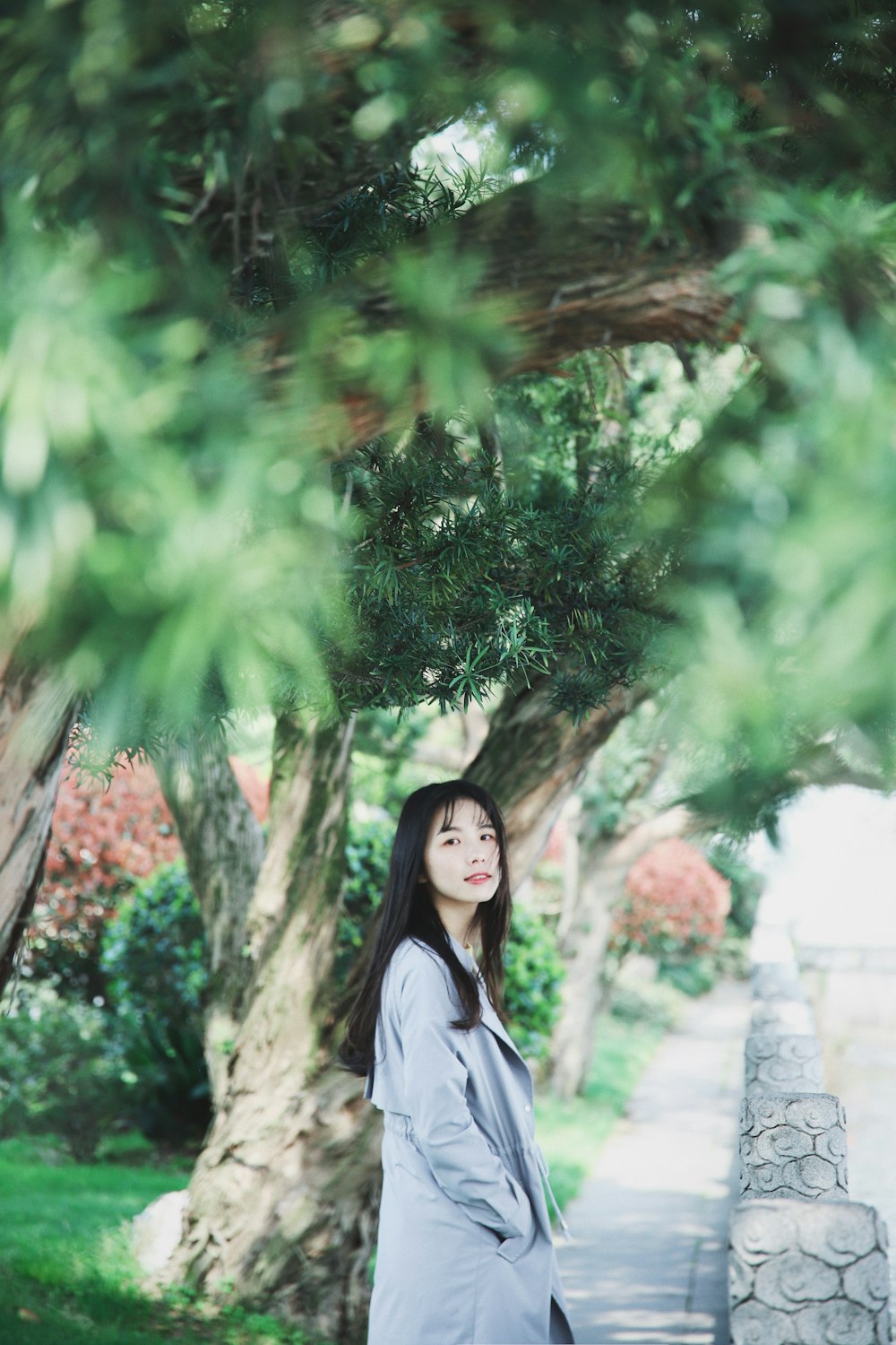 woman in white long sleeve shirt standing under green tree during daytime