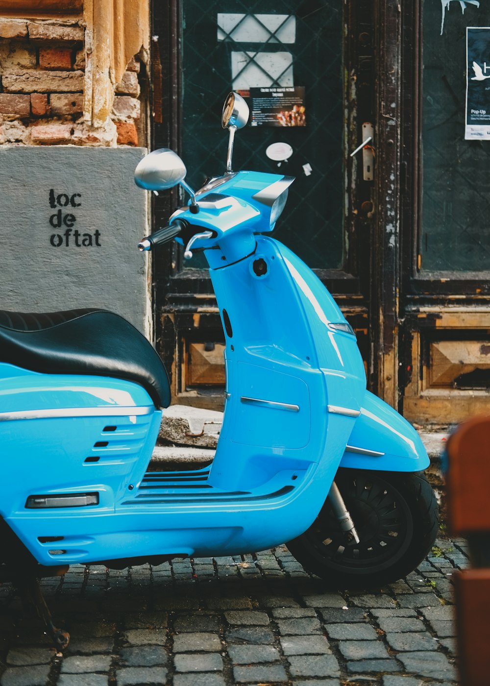 blue motor scooter parked beside wall