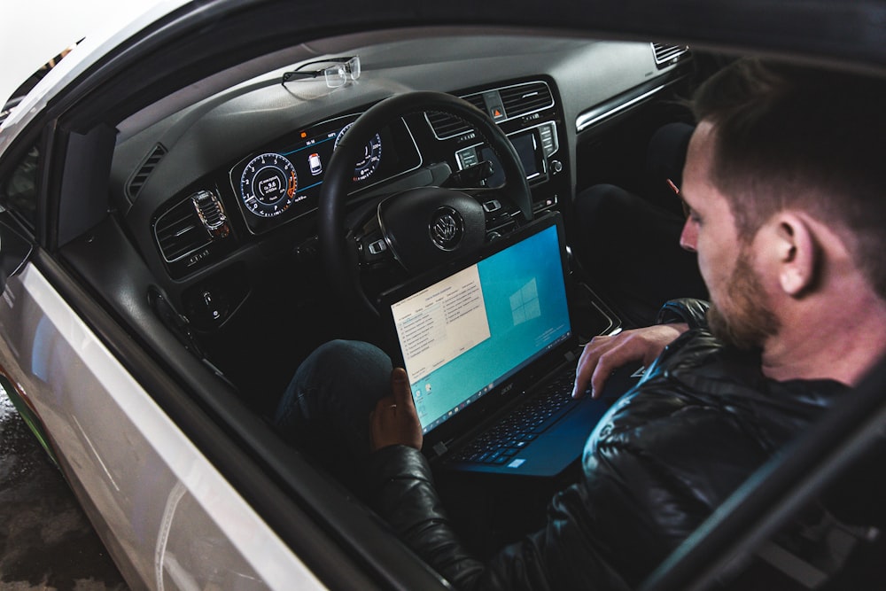 man in black jacket driving car