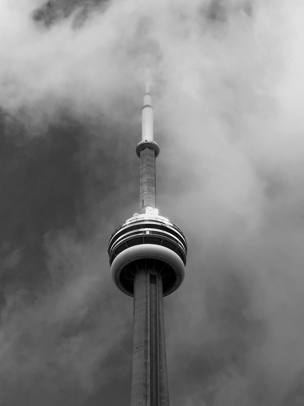grayscale photo of tower under cloudy sky