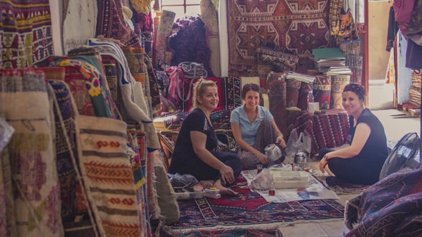 Travelers sitting cross-legged on a colorful rug, enjoying a lively conversation over a thali meal.
