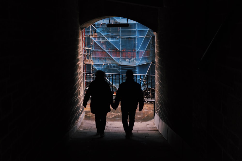 silhouette of 2 person standing in front of window