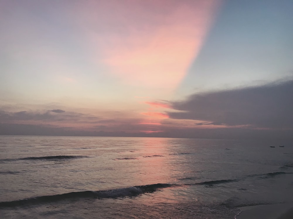 ocean waves crashing on shore during sunset