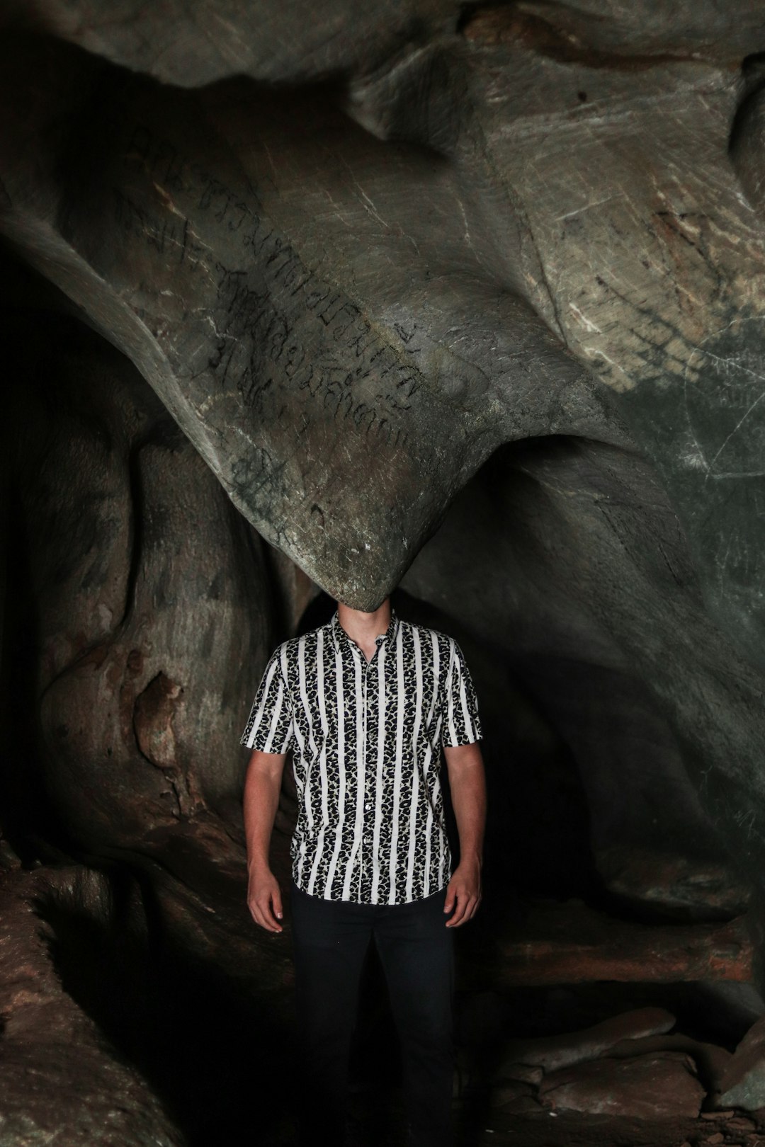 woman in black and white stripe shirt standing in cave