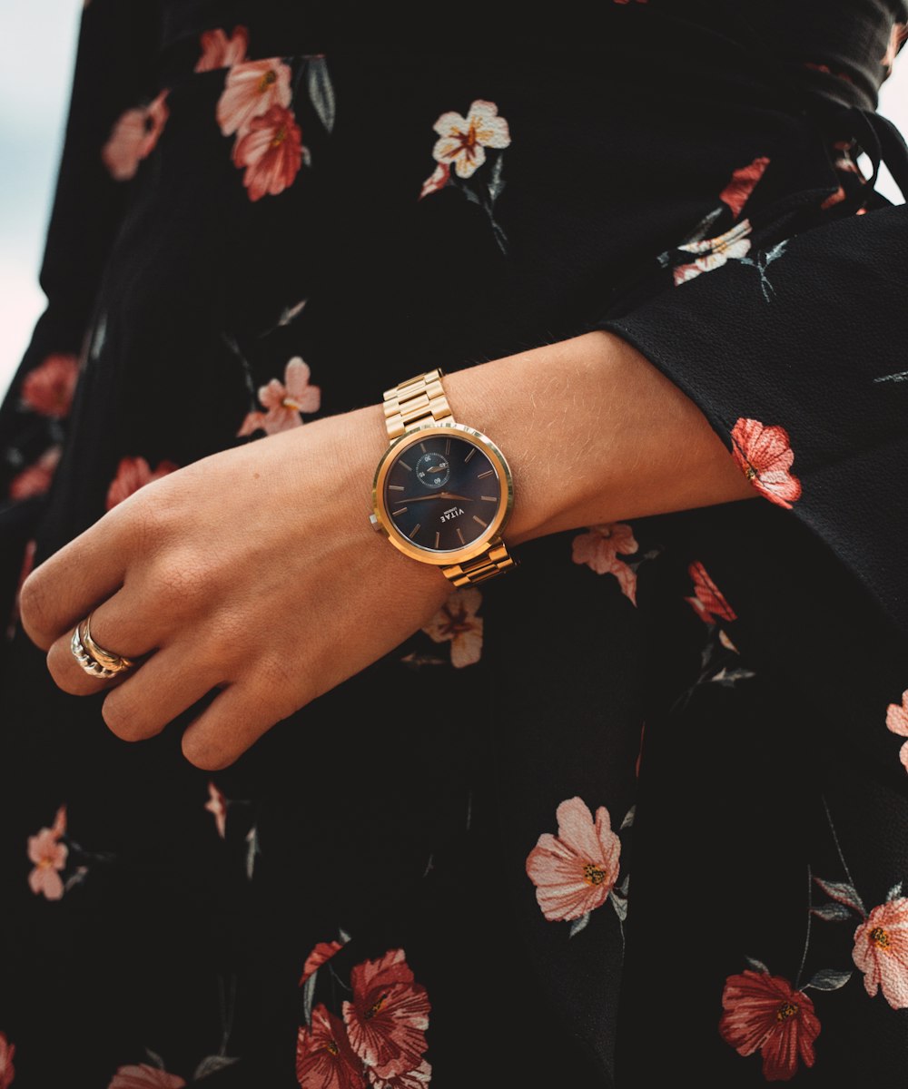 person wearing gold and black analog watch