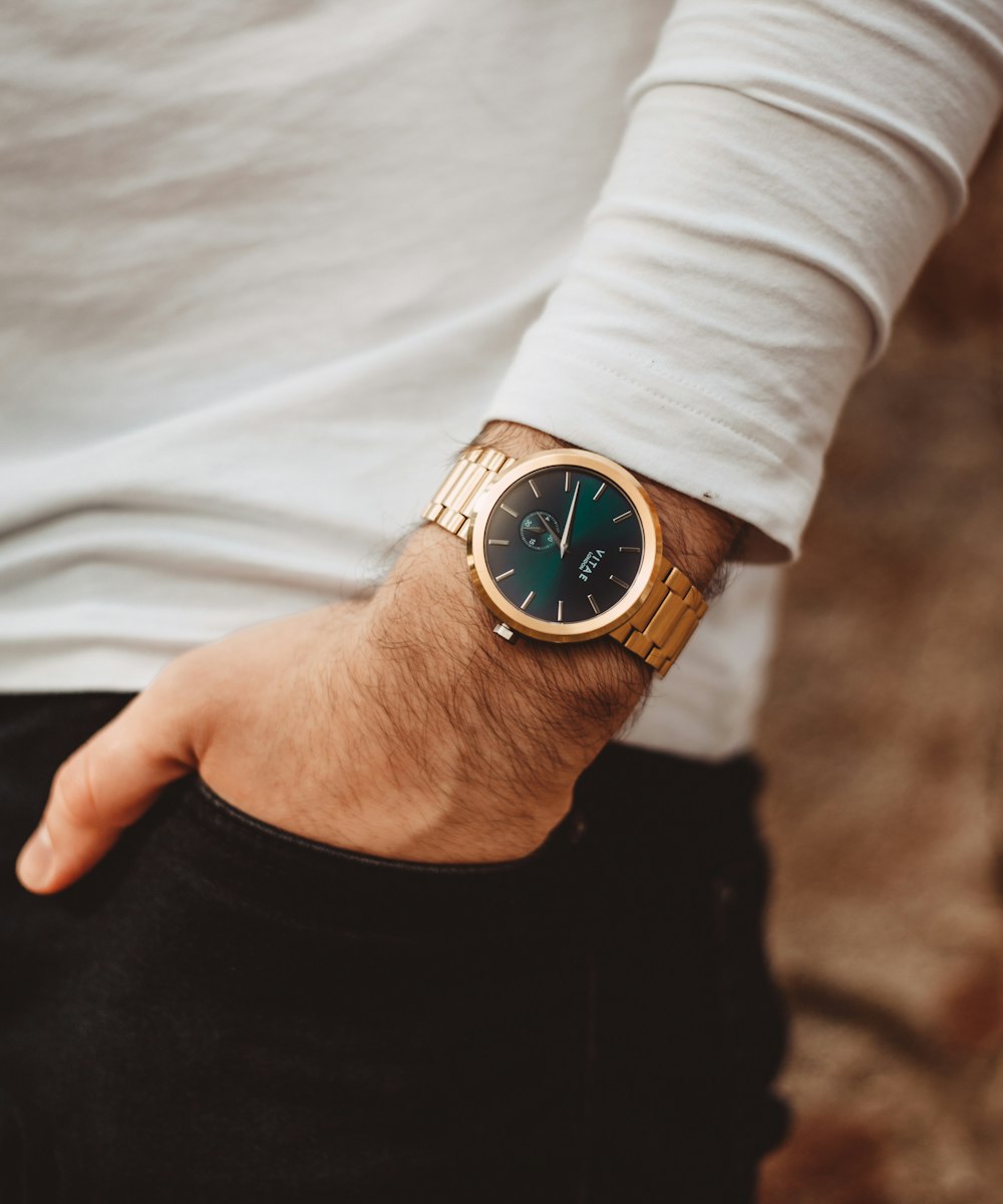 person wearing gold and blue analog watch