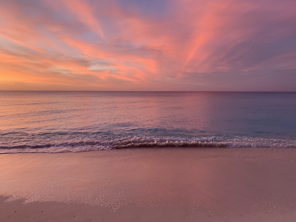 ocean waves crashing on shore during sunset