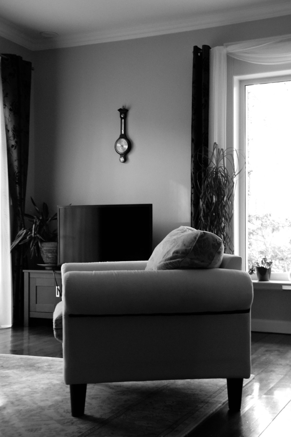 grayscale photo of sofa chair near window