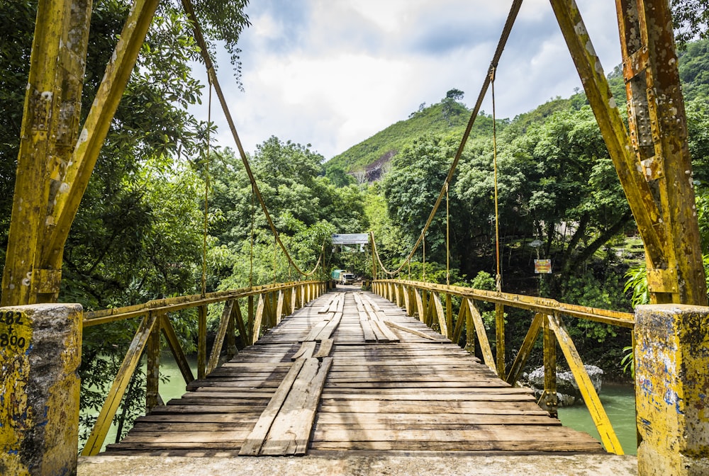 brown wooden bridge over green mountains during daytime