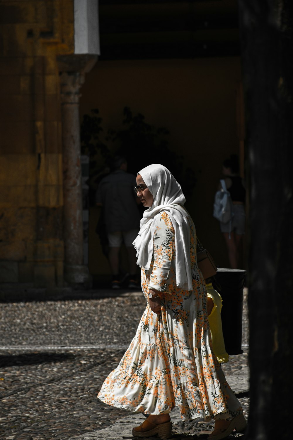 woman in white and brown dress walking on sidewalk during daytime