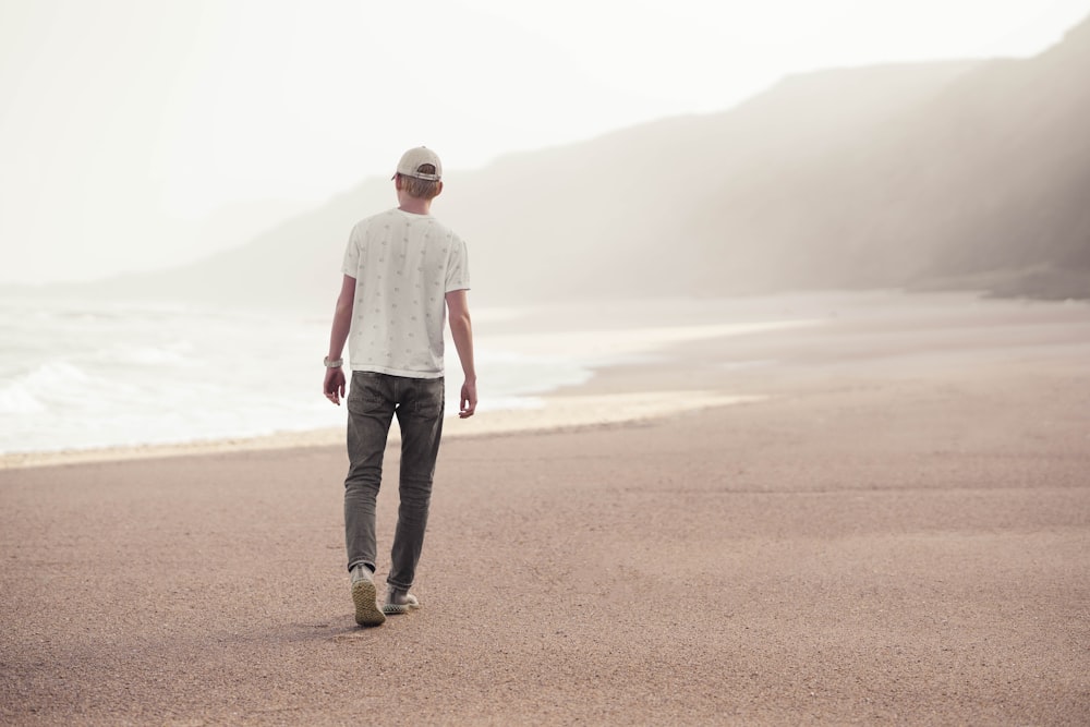 man in white dress shirt and black pants standing on brown sand during daytime