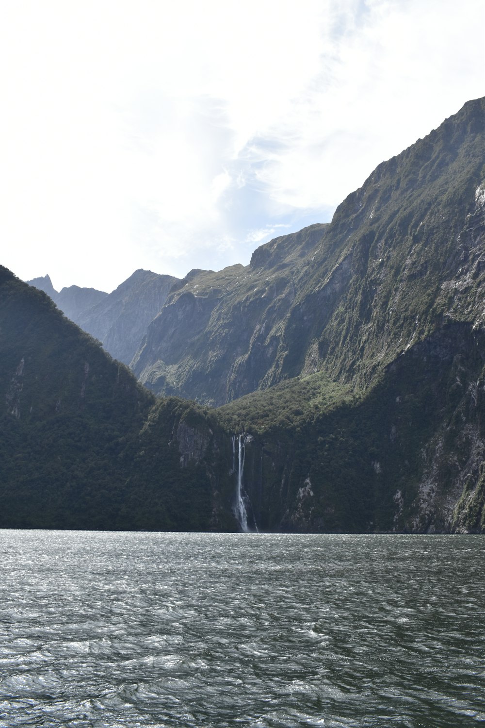 green and brown mountain beside body of water during daytime