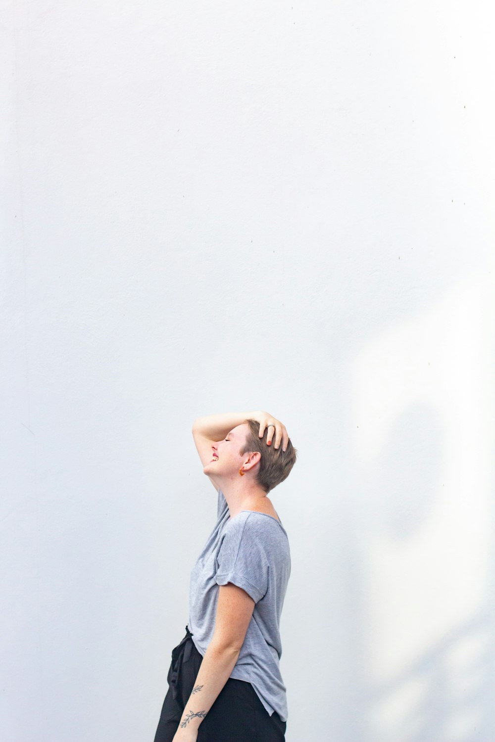 woman in gray shirt covering face with her hand