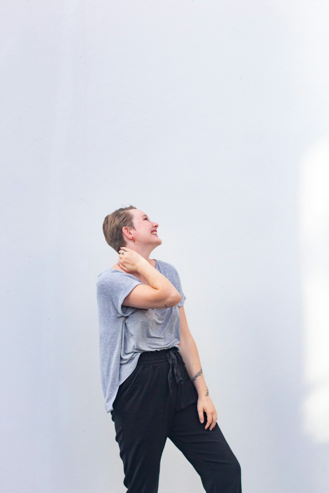 girl in gray tank top and black skirt leaning on white wall