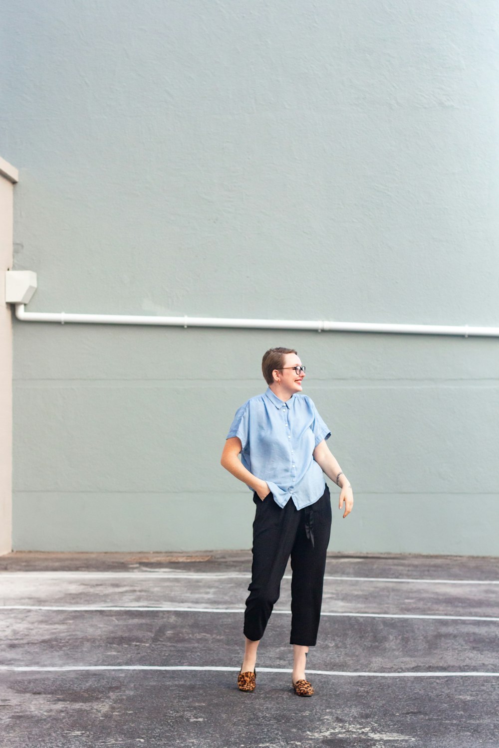 man in blue polo shirt and black pants standing beside white wall