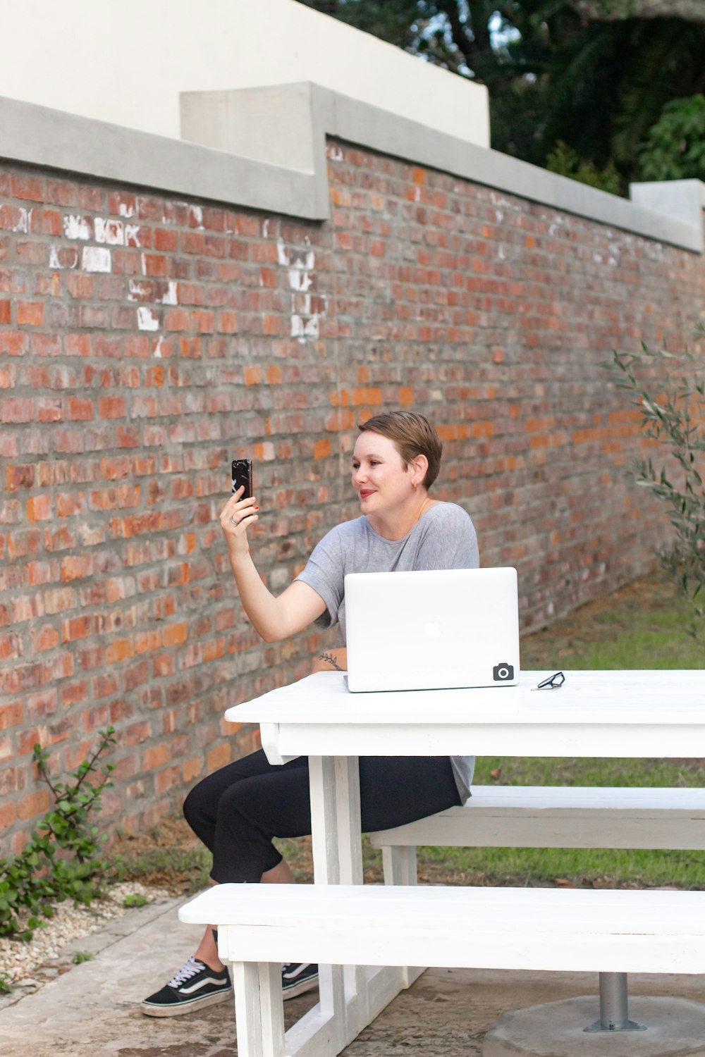 woman in gray shirt sitting on chair using macbook