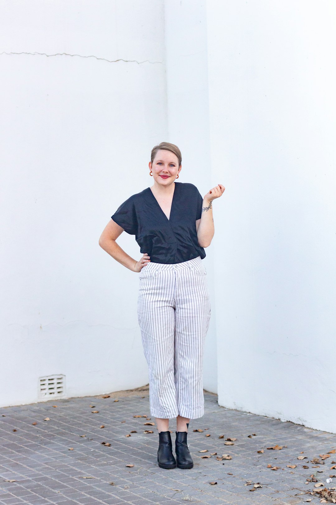 woman in black polo shirt and white pants standing on brown wooden floor