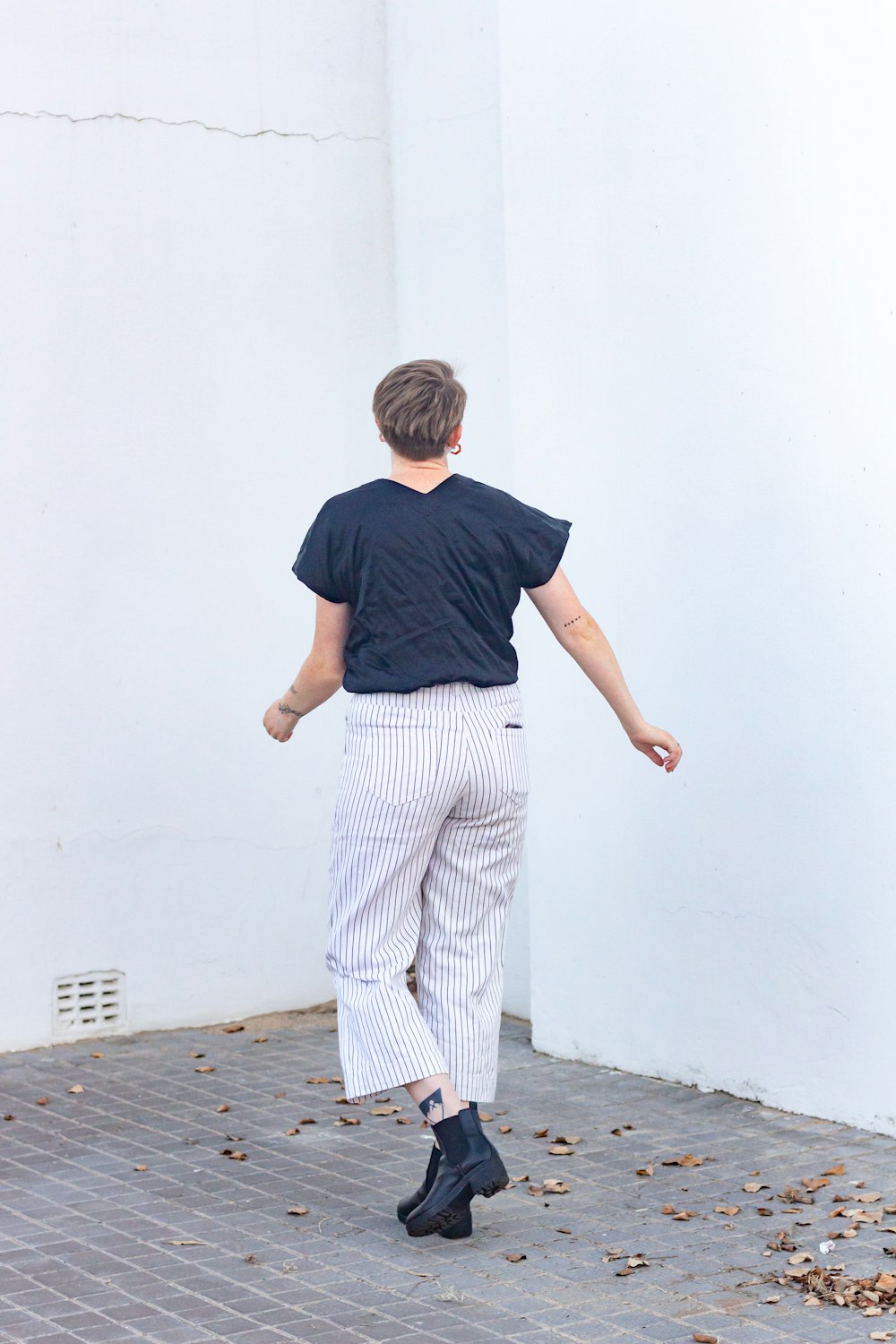 boy in blue t-shirt and white pants standing on concrete floor