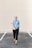 man in blue crew neck t-shirt and black pants standing on gray concrete floor