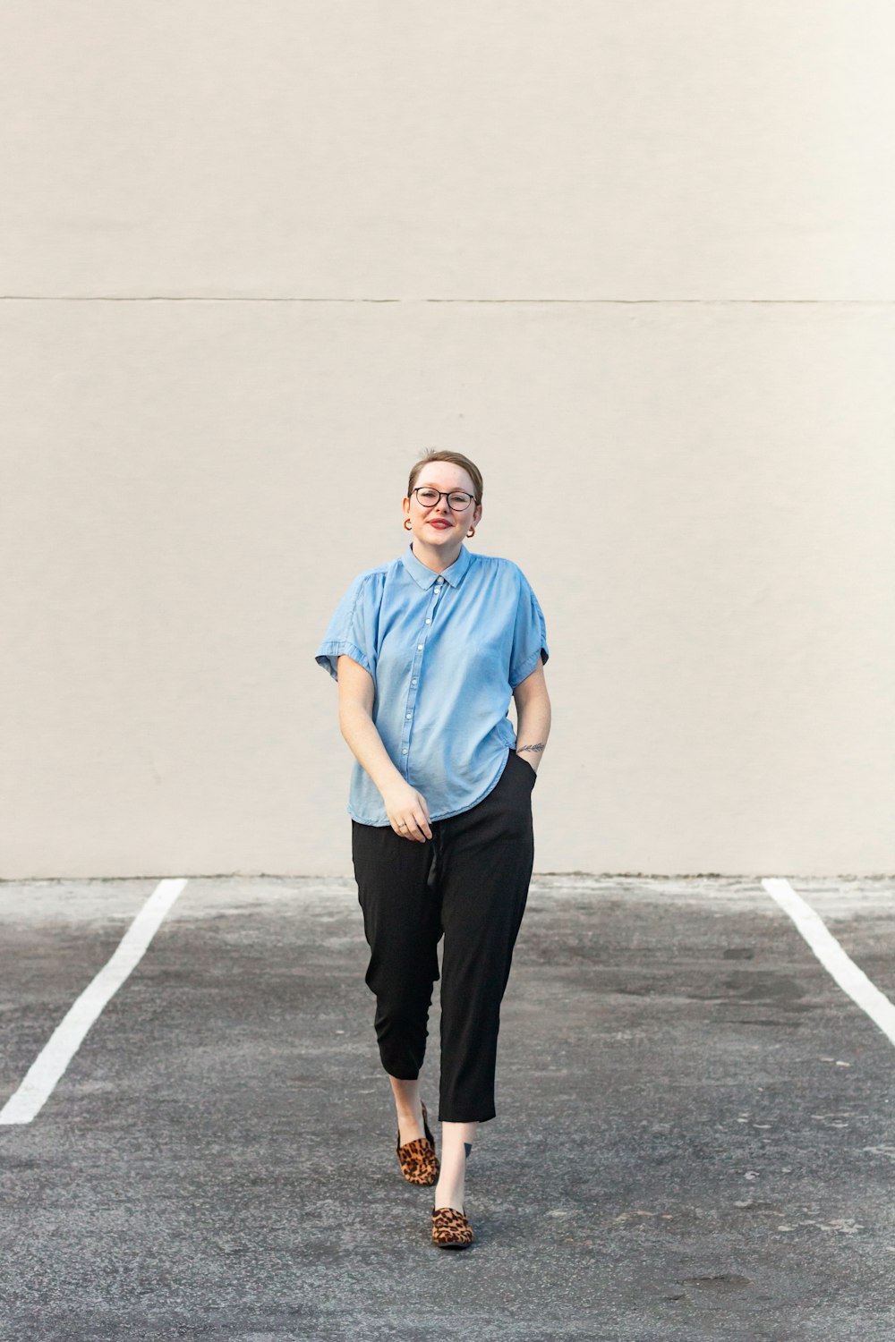 man in blue crew neck t-shirt and black pants standing on gray concrete floor