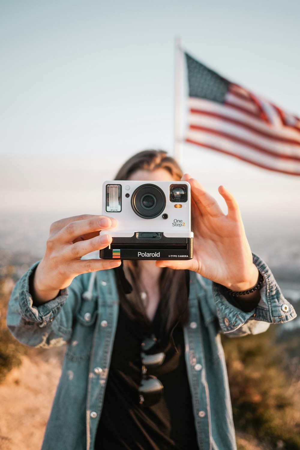 woman in blue denim jacket holding silver and black camera