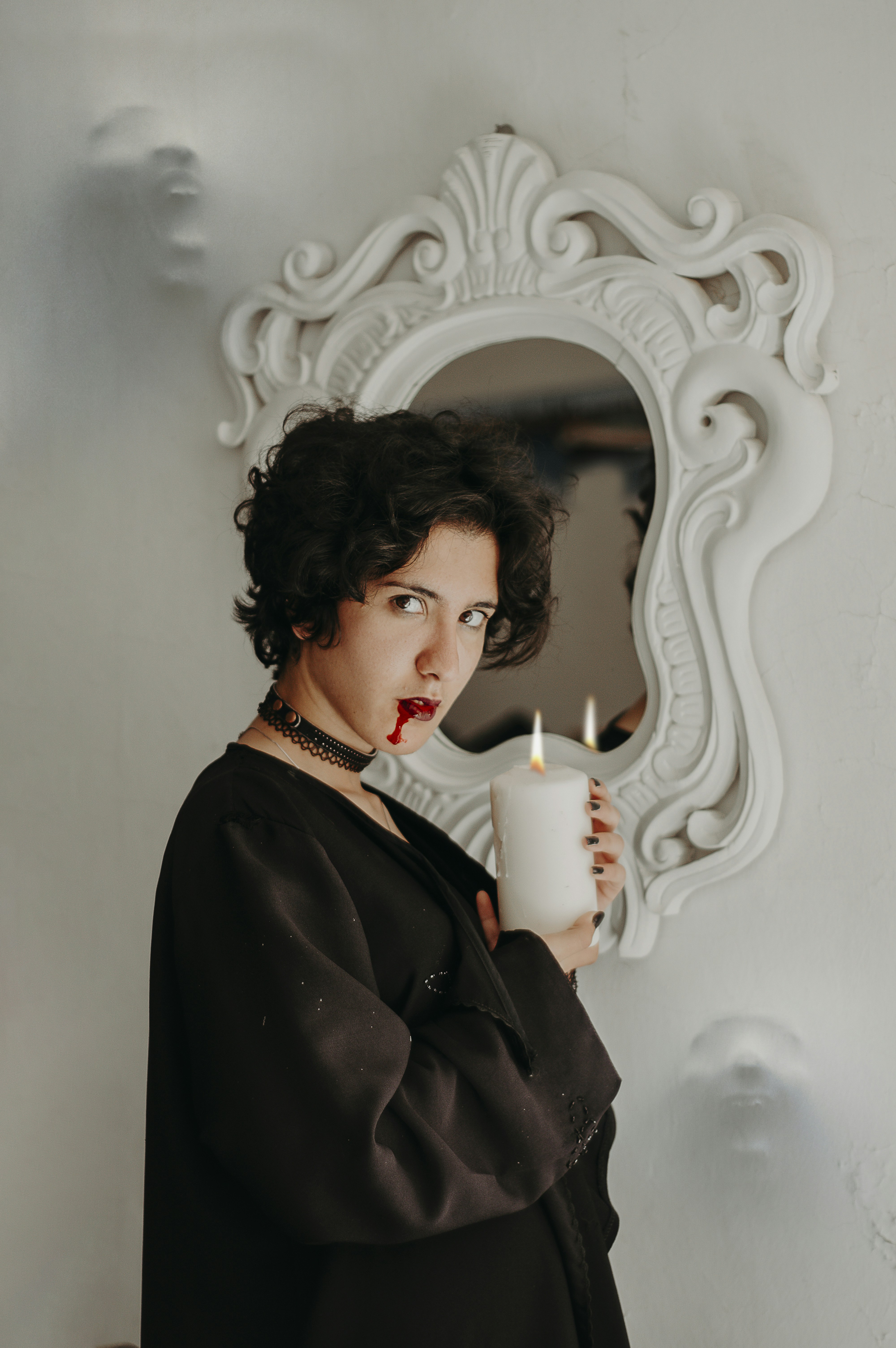 woman in black robe holding white candle