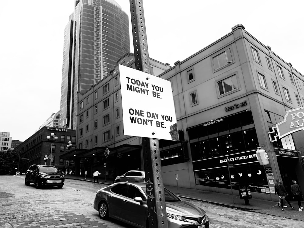 grayscale photo of cars on road near city buildings