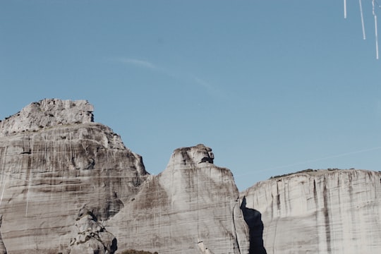 man in black jacket standing on brown rock formation during daytime in Meteora Greece