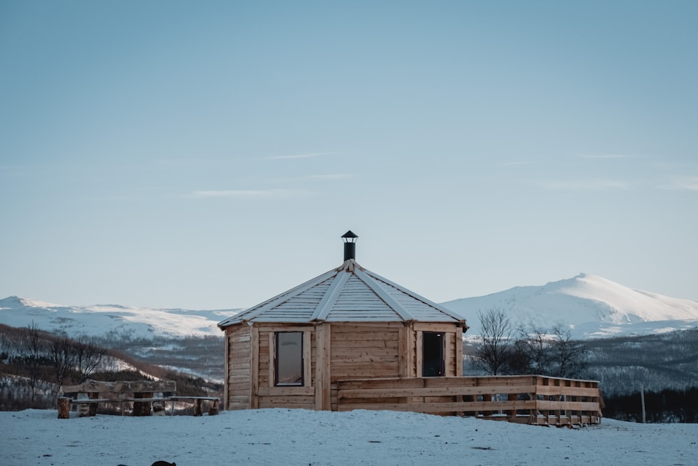 brown wooden house on snow covered ground near mountains during daytime